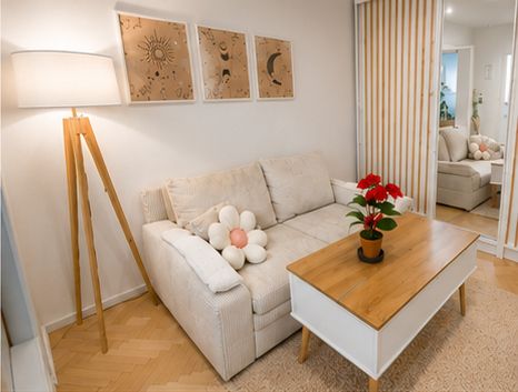 Sitzbereich mit hellem Sofa, Stehlampe, Couchtisch und drei Wandbildern.